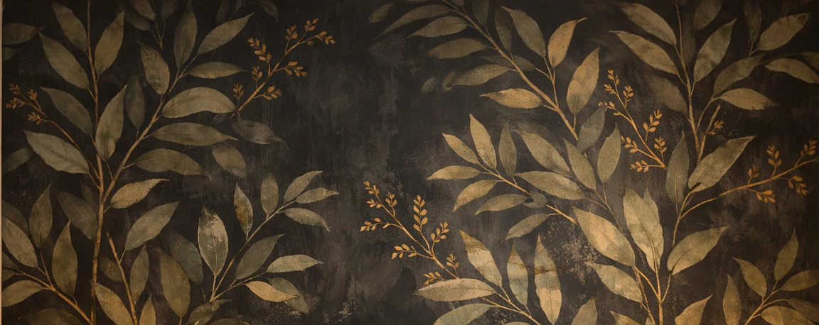 Close-up of dark moody botanical peel-and-stick wallpaper with hand-painted sage green leaves and gold accents on a charcoal background showing the accent wall pattern recommended for warm evening bedroom lighting