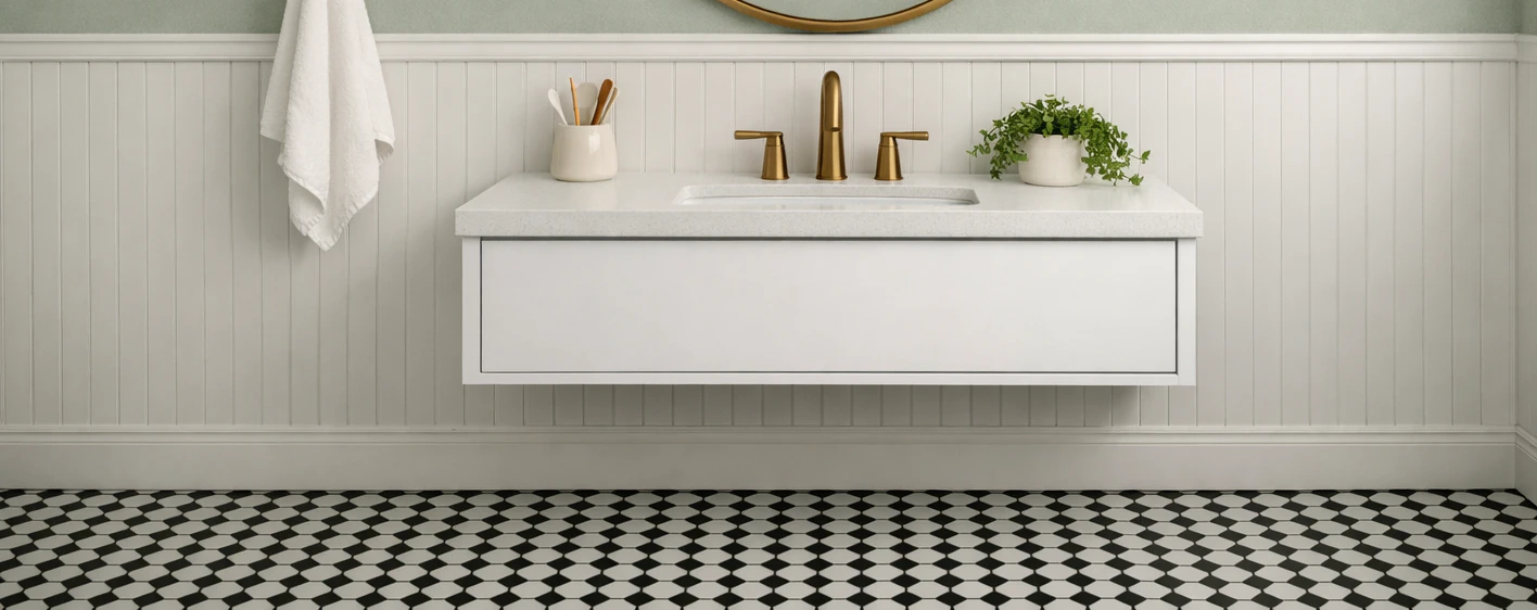 Close-up of white PVC beadboard wainscoting in a bathroom showing the vertical panel detail, a clean horizontal cap rail and a thin strip of sage-green paint above, with a white wall-mounted vanity and brass faucet centered and black-and-white hex tile floor at the bottom